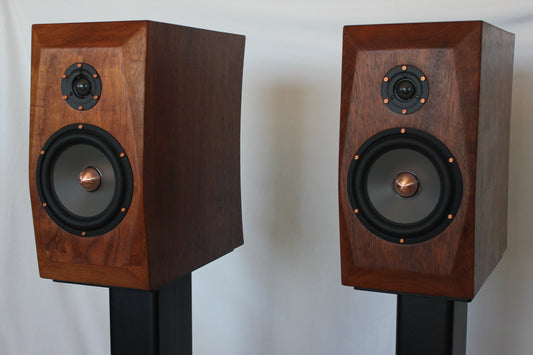 Pair of wooden speakers on stands against a white background